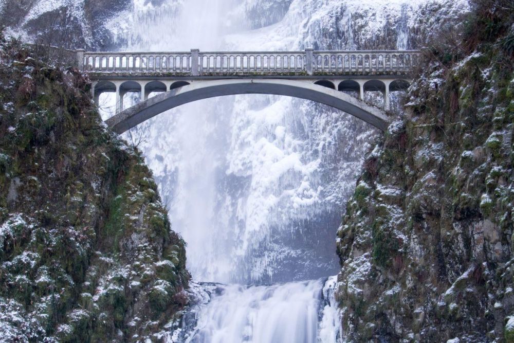 Benson Bridge crosses in front of a frozen Multnomah Falls.