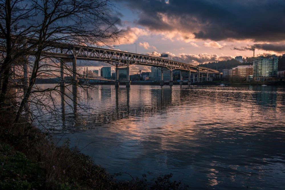 Marquam Bridge crosses the Willamette River as the sun sets behind the skyline of Portland.