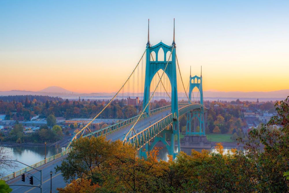 St. Johns Bridge rises above and Willamette River at twilight in Portland.