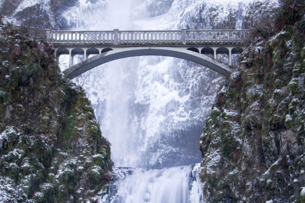 Benson Bridge crosses in front of a frozen Multnomah Falls.
